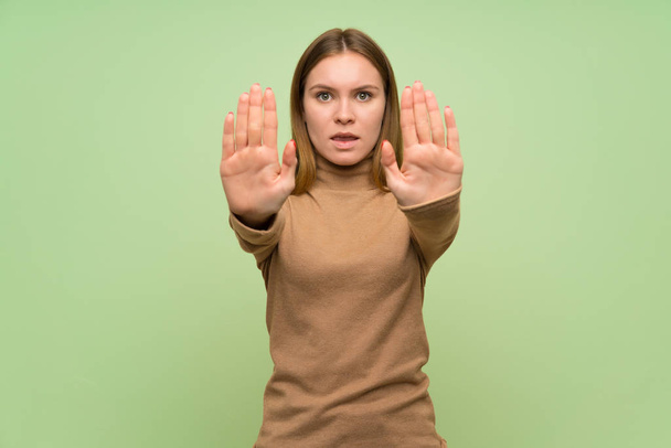 Young woman with turtleneck sweater making stop gesture and disappointed - Foto, Imagem