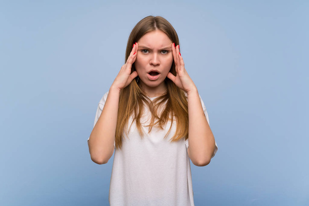Young woman over blue wall with surprise and shocked facial expression - Photo, Image