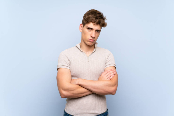 Handsome young man over isolated blue wall feeling upset - Фото, изображение