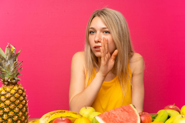 Young blonde woman with lots of fruits whispering something - Photo, Image