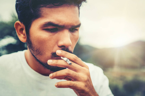 Молодий чоловік курить сигарету на відкритому повітрі
. - Фото, зображення