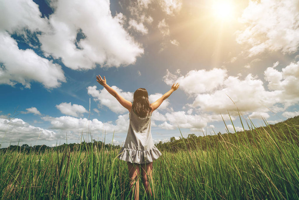 Jeune femme sur l'herbe verte écartant les bras vers le ciel
. - Photo, image