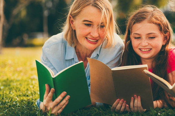 Happy family read books together in park garden. - Zdjęcie, obraz