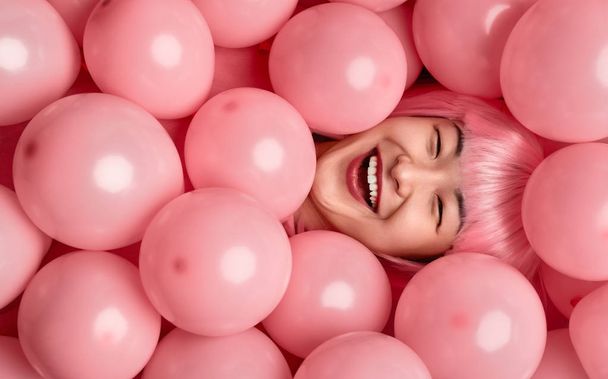 Asian female laughing under pink balloons - Φωτογραφία, εικόνα
