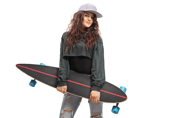 Portrait of a young trendy female holding a longboard - Фото, изображение