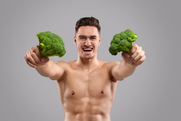 Atleta alegre mostrando brócolis
 - Foto, Imagem