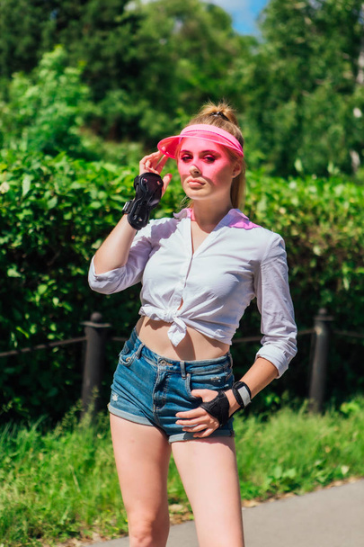Portrait of an emotional girl in a pink cap visor and protective gloves for rollerblades and skateboarding. - Foto, immagini