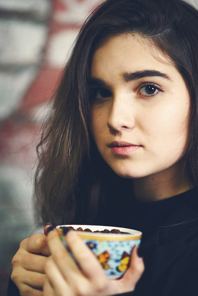 Jonge Kaukasische meisje drinken uit koffie kopje vol bonen - Foto, afbeelding