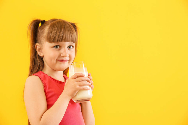 Милая маленькая девочка со стаканом молока на цветном фоне - Фото, изображение