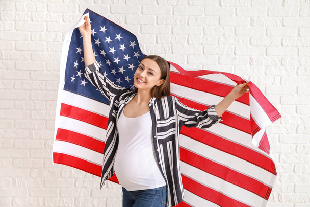 Happy pregnant woman with national flag of USA on white brick background - Foto, Imagem