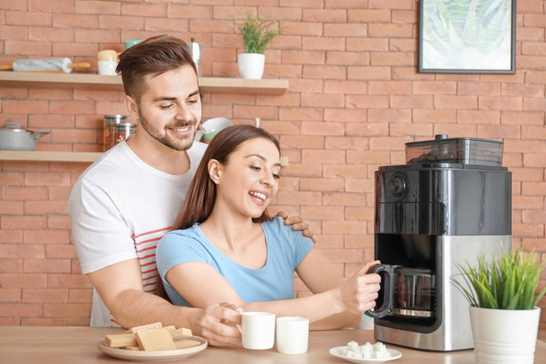 Νεαρό ζευγάρι που χρησιμοποιεί καφετιέρα στην κουζίνα - Φωτογραφία, εικόνα