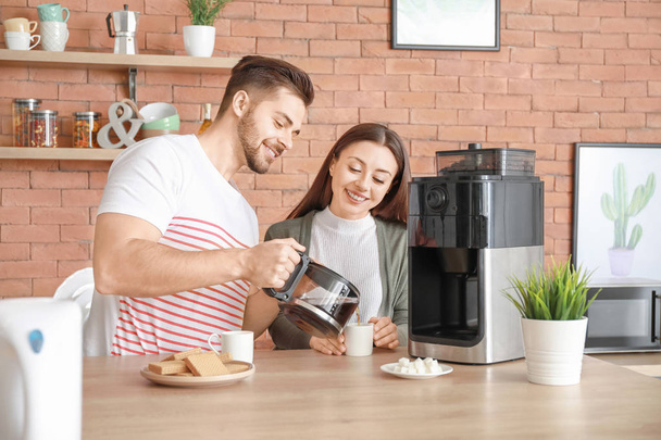 Young couple using coffee machine in kitchen - 写真・画像