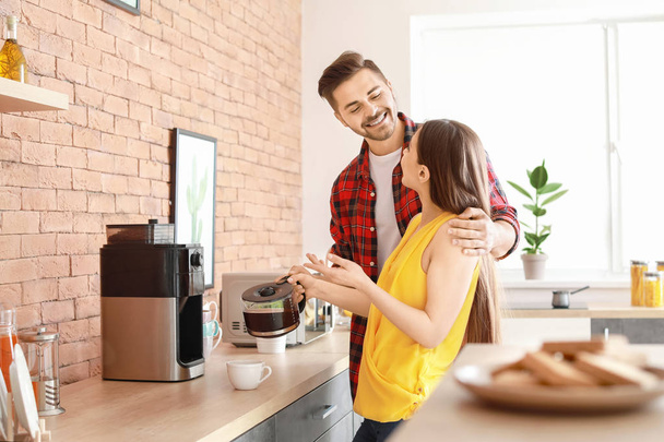 Young couple using coffee machine in kitchen - Fotografie, Obrázek