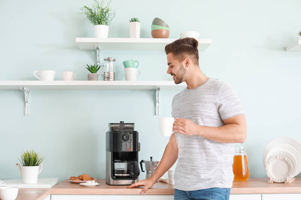 Красивый человек с помощью кофеварки на кухне
 - Фото, изображение
