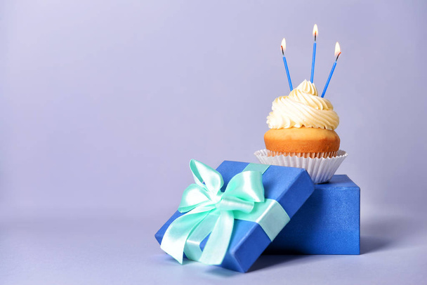 Tasty Birthday cupcake with gift box on grey background - Photo, Image