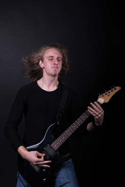 Young caucasian adult playing guitar in the studio - Foto, afbeelding