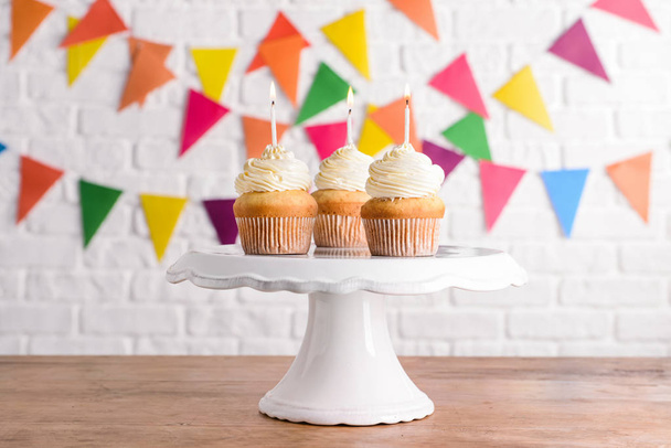 Stand with tasty Birthday cupcakes on wooden table - Photo, Image