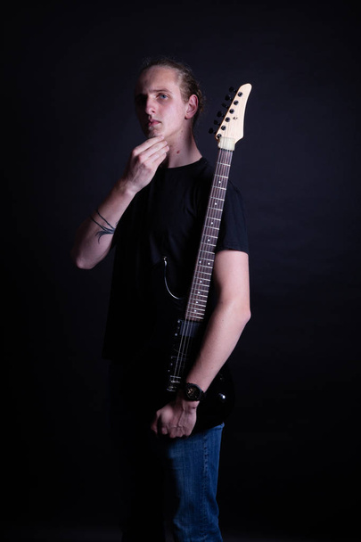Young caucasian adult posing with electric guitar in the studio - Photo, Image