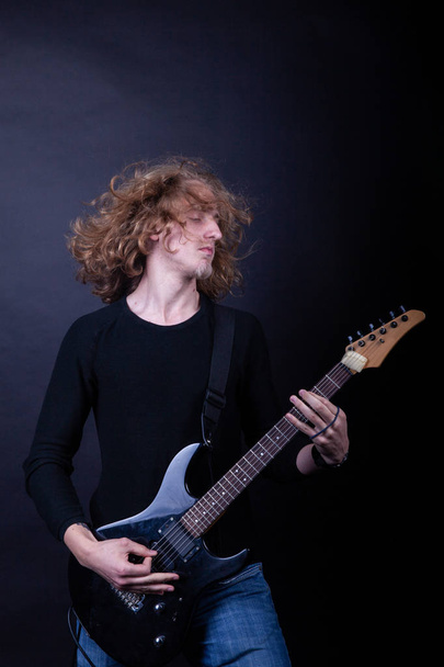 Joven caucásico adulto tocando la guitarra en el estudio
 - Foto, Imagen