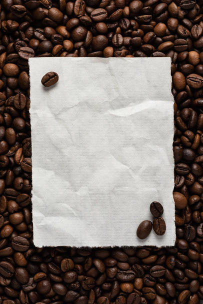 White empty sheet of paper on the background of roasted coffee beans for text menu or recipe. - Фото, зображення