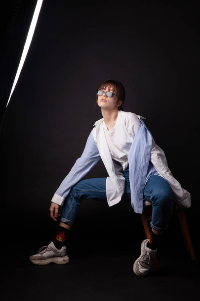 Kaukázusi lány fehér ing, fekete napszemüveg pózol a stúdióban - Fotó, kép
