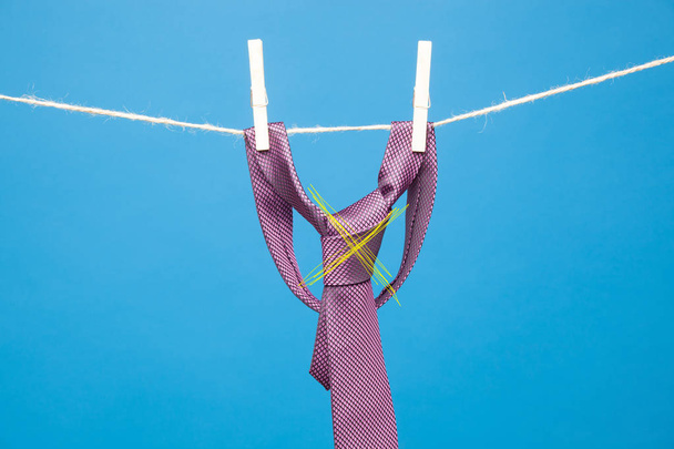 Tie with classic knot, hung on a rope and fastened by wooden clothespins to hang clothes - Foto, afbeelding