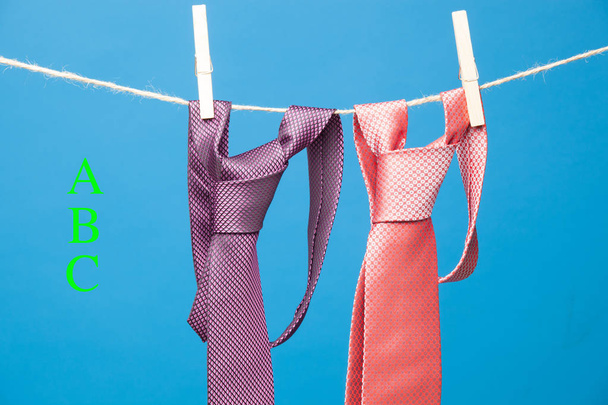 Krawatte mit klassischem Knoten, an einem Seil aufgehängt und an hölzernen Wäscheklammern befestigt, um Kleidung aufzuhängen - Foto, Bild
