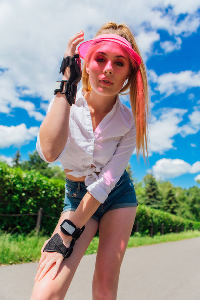 Portrait of an emotional girl in a pink cap visor and protective gloves for rollerblades and skateboarding. - Фото, зображення