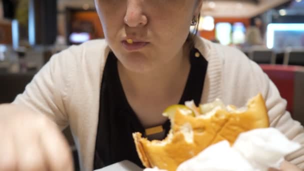 Fast food restoranında patates kızartması ve hamburger yiyen kadın, ağız yakın çekim. - Video, Çekim