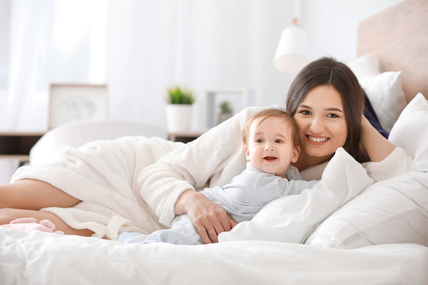 Happy mother with adorable baby boy on bed at home - Фото, изображение