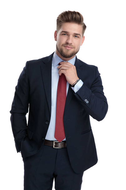 Серьёзно выглядящий бизнесмен, регулирующий свой красный галстук
  - Фото, изображение