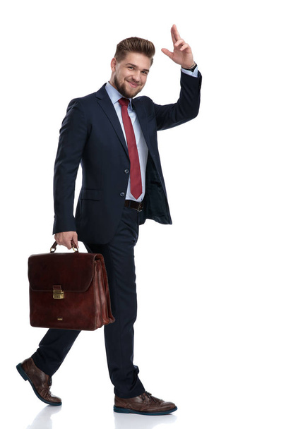 Young businessman holding his briefcase and greeting - Photo, image