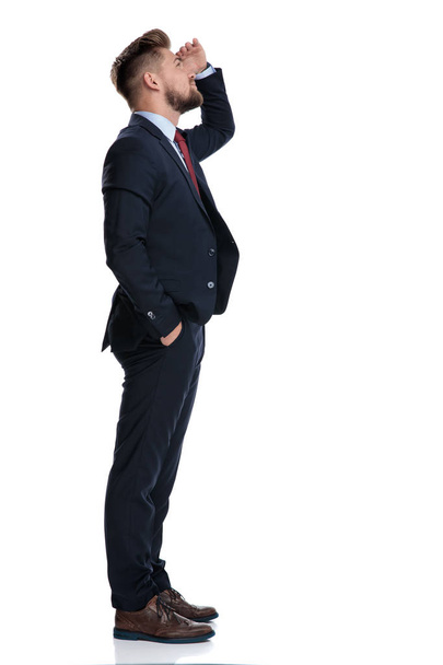 Vista lateral de un hombre de negocios ansioso mirando hacia arriba
 - Foto, Imagen