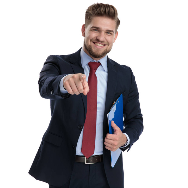 Cheerful businessman pointing and holding a clipboard  - Фото, изображение