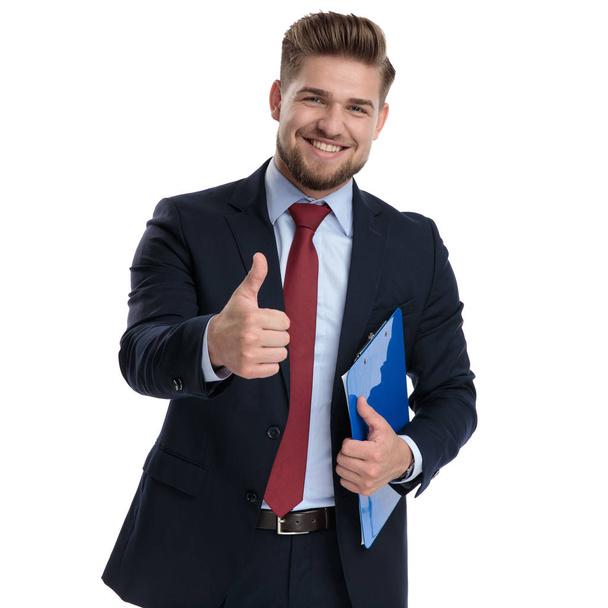 Happy businessman gesturing ok and holding a notepad - Foto, afbeelding