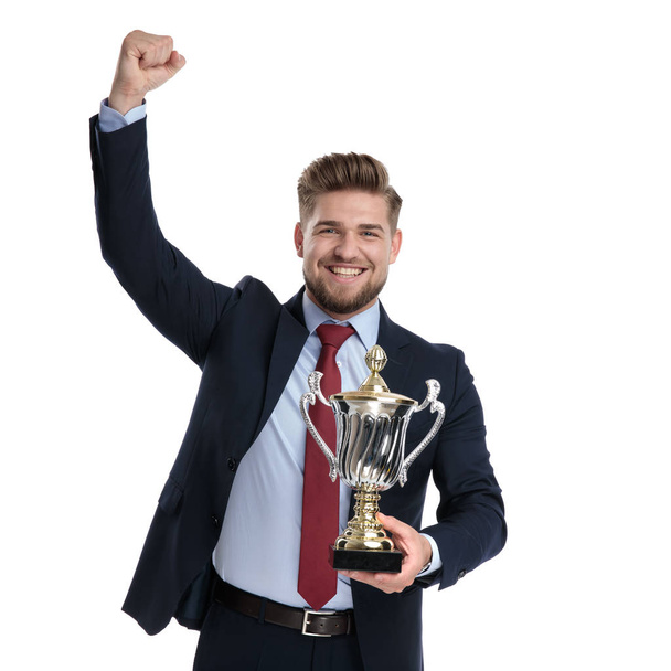 Випадковий бізнесмен святкує і тримає трофей
  - Фото, зображення