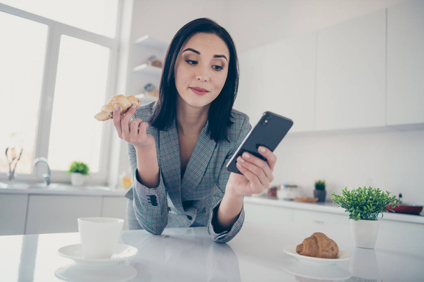 Close up photo beautiful she her corporate lady look telephone report hands arms fresh croissant hot beverage table coffee pause rest formal-wear checkered plaid costume bright white kitchen indoors - Photo, image