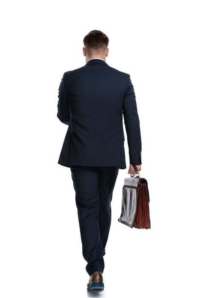 Vista posterior de un empresario motivado sosteniendo su maletín
 - Foto, Imagen