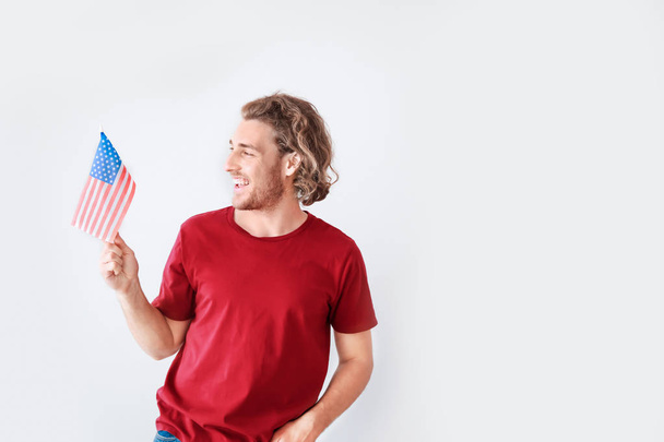 Happy young man with USA flag on white background. Independence Day celebration - Zdjęcie, obraz