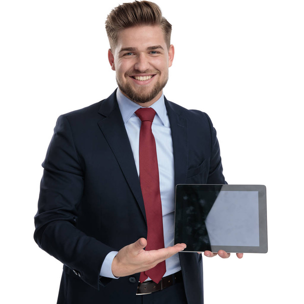 Happy businessman presenting his table while smiling  - Photo, Image