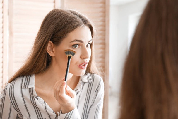 Mujer joven cerca del espejo en la sala de maquillaje
 - Foto, Imagen
