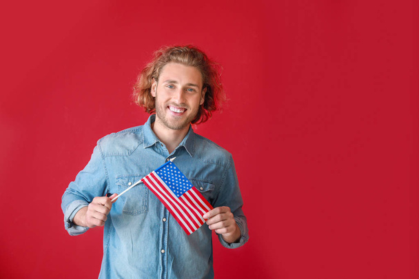 Happy young man with USA flag on color background. Independence Day celebration - Фото, изображение