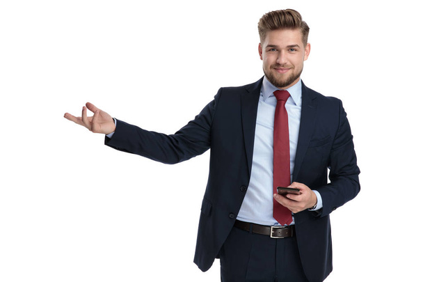 Уверенный бизнесмен представляет и держит свой телефон
  - Фото, изображение