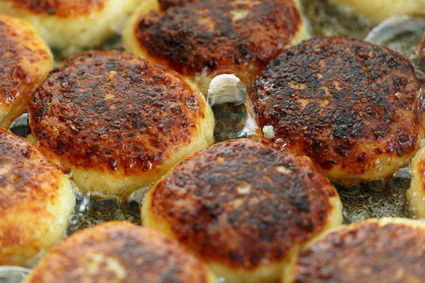 Kookproces van heerlijke gebakken syrniki close-up in de pan. Traditioneel in Oekraïne, Belarus en Rusland. Concept van een gezonde huisgemaakte maaltijd. - Foto, afbeelding