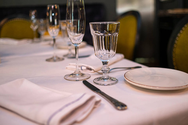Natural light or daylight shot of modern restaurant table set for a lunch. Shallow focus on wine glass. Empty glasses set in restaurant. - 写真・画像