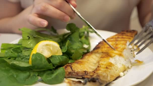 Mies syö paistettua kalaa haarukalla ja veitsellä ravintolassa, lautasen lähikuva
. - Materiaali, video
