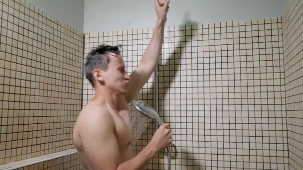 Man sings with enthusiasm using shower as a microphone taking a shower. - Video