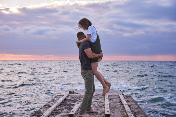dvojice zamilovaná stojí a setkuje se s východem slunce na molu. oceán nebo Mořský břeh - Fotografie, Obrázek