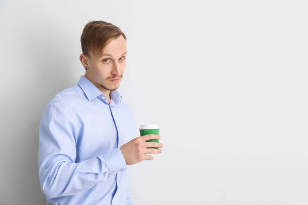 Handsome businessman with cup of coffee on light background - Photo, Image