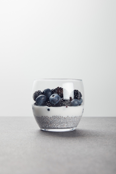 tasty yogurt with chia seeds, blueberries and blackberries on marble surface isolated on grey - Foto, Imagen
